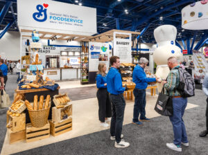 trade show attendees stop to sample General Mills baked goods while the Pillsbury Doughboy looks on.